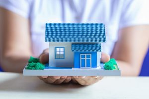 Human hands holding model of dream house, loans and investments concept