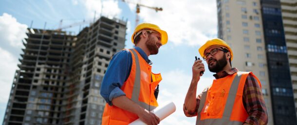 Contractor speaking on walkie-talkie with co-worker near by